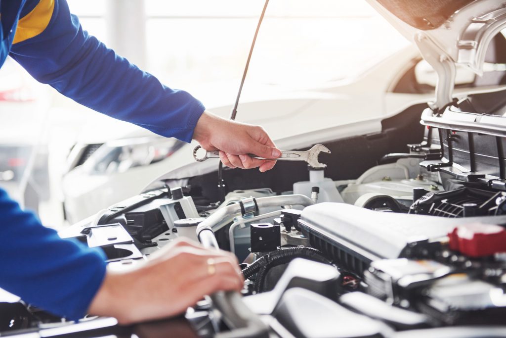 Hands of car mechanic with wrench in garage