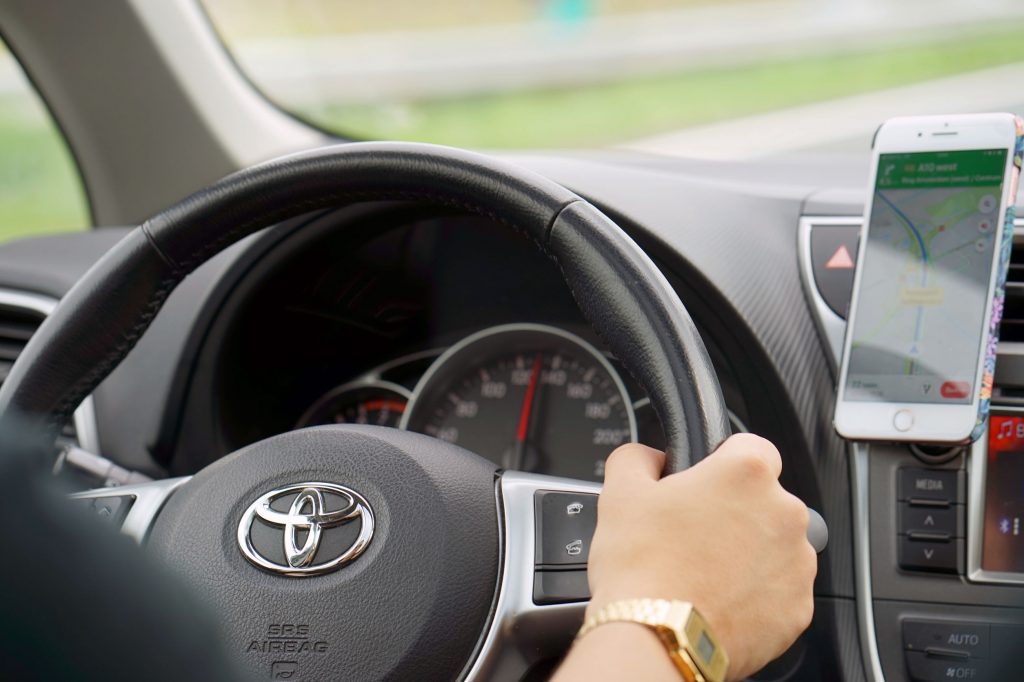 Hands of man with a steering wheel, Driving a car on a smartphone navigator. Photo of a man driving a car. Rear view and rear view of male driving a car Toyota. 31 August 2018. Speed track Den Haag Amsterdam. Holland.